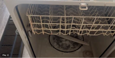 Inside a dishwasher showing the lower rack and spray arm